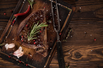 Grilled tasty beef steak on black stone table. Top view.
