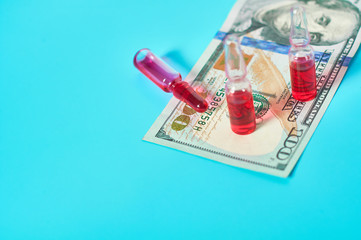 Banknote of 100 usd and red vaccine on green background. Corruption in medicine. Purchasing medications in pharmacy. Drugs donations. Payment for treatment. Health сare concept
