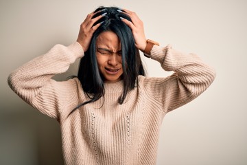 Young beautiful chinese woman wearing casual sweater over isolated white background suffering from headache desperate and stressed because pain and migraine. Hands on head.