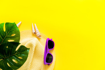 Accessories flatlay traveler on a yellow background is a hat, sunglasses and a green plant. The concept of a trip or vacation with a view from above. Summer background