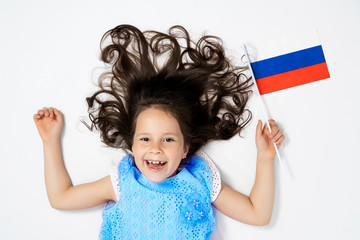a beautiful girl lies on a white background next to the flag of Russia. the view from the top