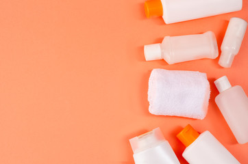 Beauty background with facial cosmetic products on coral background. Modern spring skin care layout, top view, flat lay.