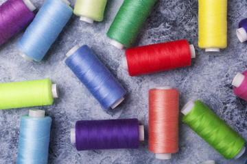 Colorful threads on bobbins, sewing set.On gray concrete background. Place for text.