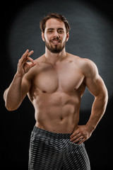 Fototapeta na wymiar A handsome muscular man without a t-shirt poses for a photographer in a dark photo Studio. The concept of sport