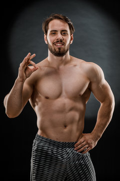 A handsome muscular man without a t-shirt poses for a photographer in a dark photo Studio. The concept of sport