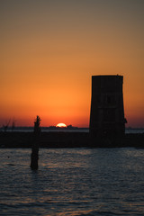 Naklejka premium atardecer sobre el lago y una torre muy rojo muy naranja silueta de torreon