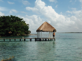 Turquoise waters in Laguna Bacalar, Quintana Roo, Mexico. Wooden walkway over crystal clear waters. Log cabin. Copy space photography