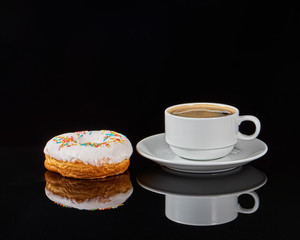 Donut and white coffee cup with coffee on a black background.