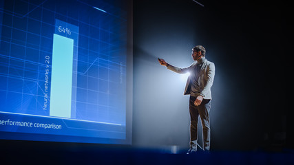 On-Stage: Handsome Speaker Does Presentation, New Product Release, Shows Infographics, Statistic Animation on Big Screen. Auditorium Hall Live Event, Start-up Conference, Device Presentation.
