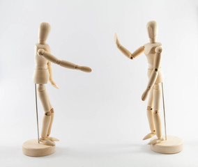 Wooden puppets on white background with social distancing concept. Gesture of one puppet refusing...