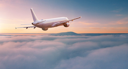 Commercial airplane jetliner flying above dramatic clouds in beautiful light. Travel concept.