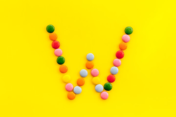 Letter W - alphabet made with sweets on yellow from above
