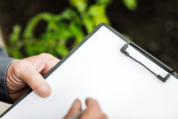 Close-up of the farmer's hands. The farmer records observations in a tablet. Concept of agriculture and crop production.