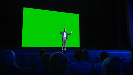 On Stage, Keynote Speaker Presents New Product to the Audience, Behind Him Movie Theater with Green...