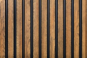A fence made of vertical wooden decorative strips located parallel to each other.