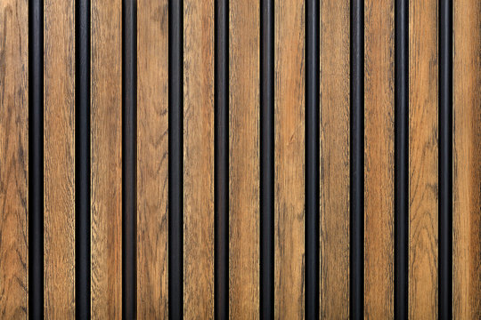 A fence made of vertical wooden decorative strips located parallel to each other.