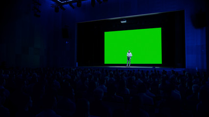 Keynote Speaker Does Presentation of New Product to the Audience, Behind Him Movie Theater with...