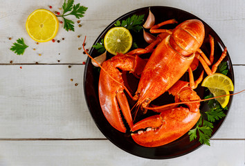 Boiled lobster in a black plate with lemon and parsley.