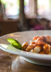 ñoquis con salsa roja y una hoja de albahaca con vapor y fondo desenfocado
