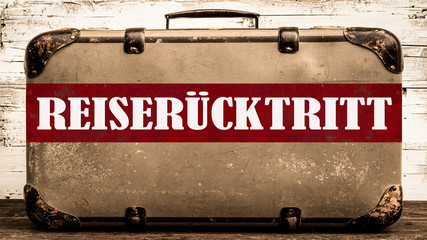 CORONA-REISEWARNUNG - Alter rustikaler vintage Koffer mit rotem Banner und weißem Schriftzug...