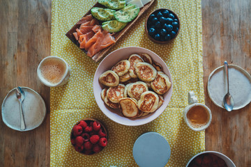 Top view of delicious breakfast with mini pancakes, berries, salmon and avocado, Trendy morning homemade breakfast