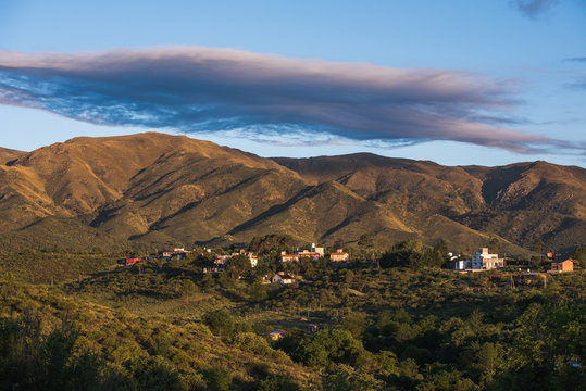 sierras de cordoba con cielo con algunas nubes y casas en la base de la sierra
