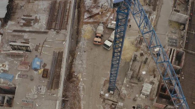 Aerial shot of assembly crane, construction site with building materials and equipment and a pair of concrete mixer machines. Repair and development of the city with new modern buildings for housing.