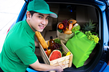 Asian delivery man in green t-shirt delivering food, fruit, joice and vegetable to home - online grocery shopping service concept