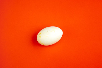 Minimalism concept of white flat lay with one egg isolated on red paper textured background.
