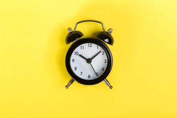 black vintage alarm clock on a colored background, top view. concept of time, daily routine