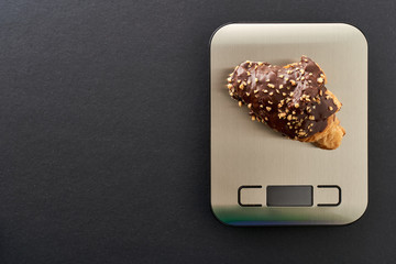 Top view of some chocolate sweets on a kitchen scale to control the diet. Concept of diet and food control.