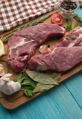 seasoning meat with tomatoes garlic lemon rosmary cucamber wooden background