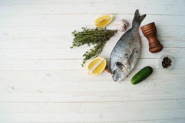 Raw fish cooking and ingredients. Dorado, lemon, herbs and spices. Top view on stone table