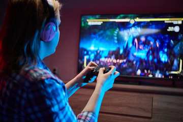 Portrait of crazy playful Gamer, girl enjoying Playing Video Games indoors sitting on the sofa, holding Console Gamepad in hands. Resting At Home, have a great Weekend