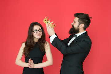 Prom party. Happy girl enjoy crowning. Bearded man crown beauty queen. Coronation party. Couple in love red background. Valentines party. Success and triumph. Happy party celebration