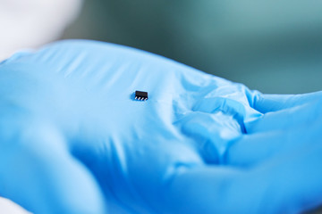 Hand holds chip compenent. Embedding the chip under human skin, microcontroller implanting NFC...