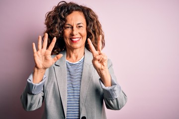 Middle age beautiful businesswoman wearing elegant jacket over isolated pink background showing and pointing up with fingers number seven while smiling confident and happy.