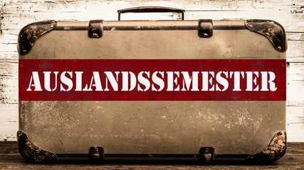 Alter rustikaler vintage Koffer mit rotem Banner und weißem Schriftzug 