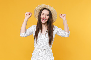 Funny young brunette woman girl in white dress hat posing isolated on yellow wall background studio portrait. People sincere emotions lifestyle concept. Mock up copy space. Clenching fist like winner.