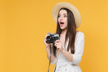 Shocked young brunette woman girl in white dress hat posing isolated on yellow wall background in studio. People lifestyle concept. Mock up copy space. Taking pictures with retro vintage photo camera.