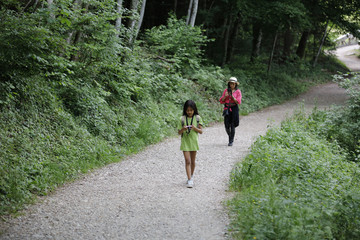 A mother and her daughter looks on their smartphones in the forest