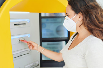 Woman with antiviral mask at ATM