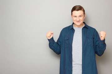 Portrait of happy proud man raising fists up in triumph