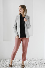 .girl in a gray jacket with a black shirt and full-length powdery trousers posing in the studio. dress code. business