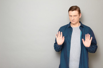 Portrait of serious man showing palms and asking to keep distance