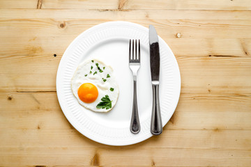 Fried eggs on plate - light wooden kitchen table top-down