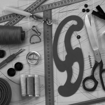 on a paper pattern are tailor's scissors, a pattern with a ruler and other sewing tools and accessories