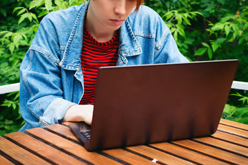 Closeup portrait of young adult female freelancer working on her laptop outside