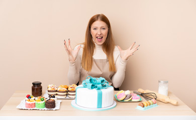 Obraz na płótnie Canvas Young redhead woman with a big cake unhappy and frustrated with something