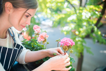 Fototapeta premium Woman looking at flowers on balcony checking for pests and diseases